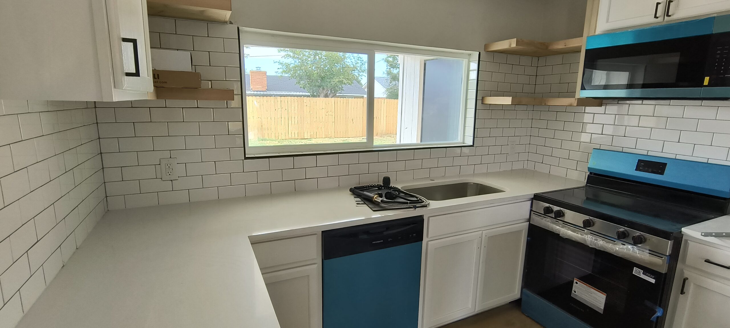 Experienced Austin TX remodeling contractor Cuatro Pilares completing modern kitchen remodel with white cabinets, subway tile backsplash, and upgraded appliances