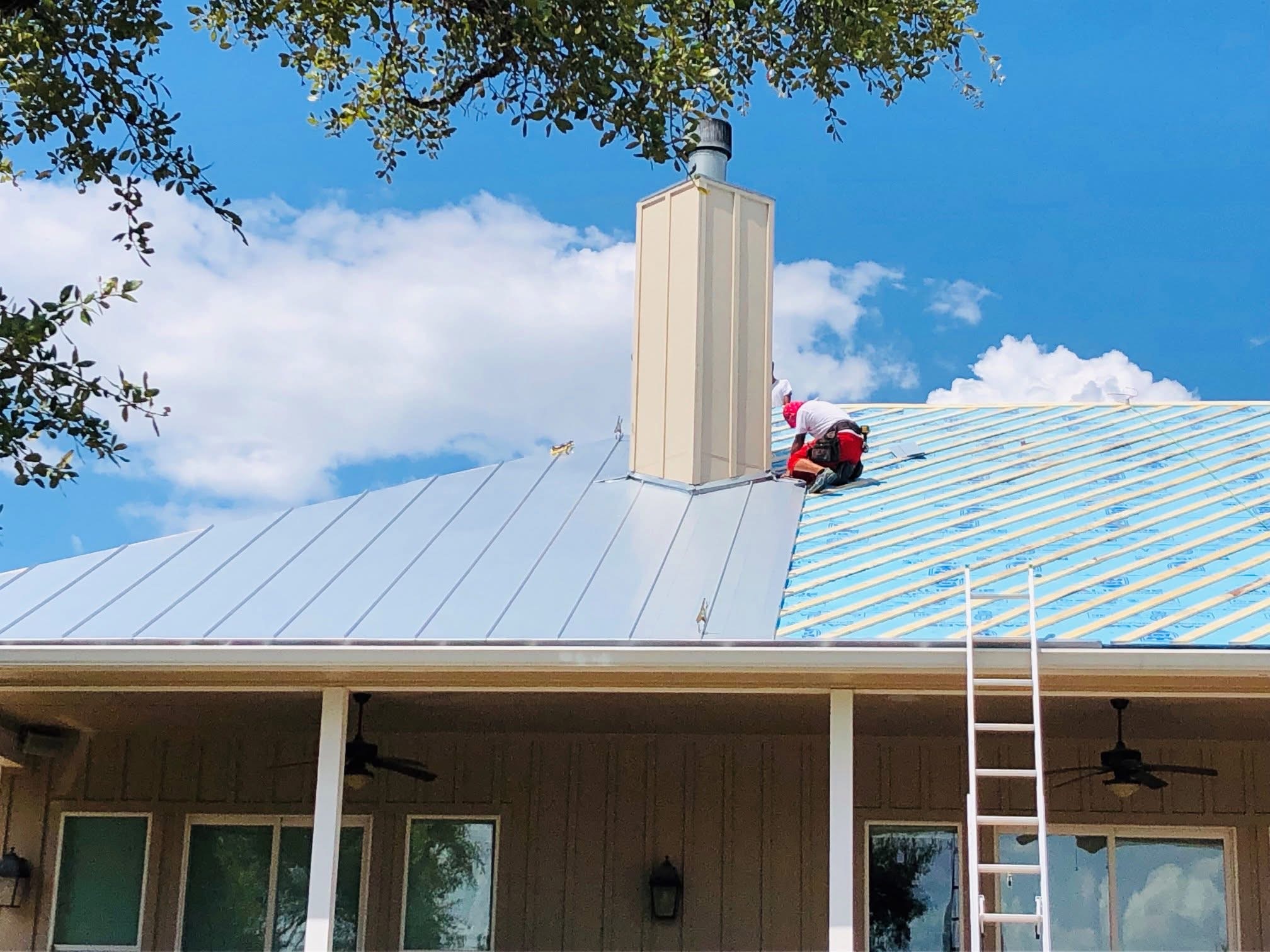 Experienced Austin TX roofing contractor Cuatro Pilares installing standing seam metal roof with precision chimney flashing on residential home