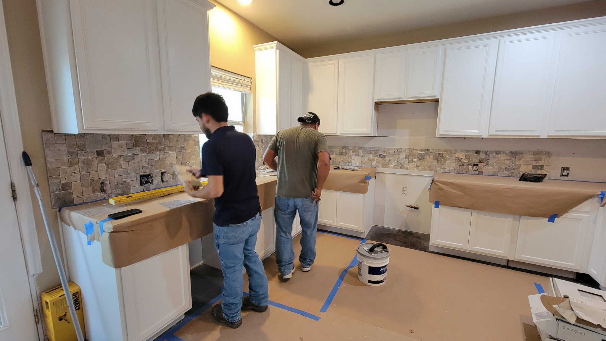 Experienced Cuatro Pilares team completing kitchen remodel in Austin TX with backsplash and cabinet installation
