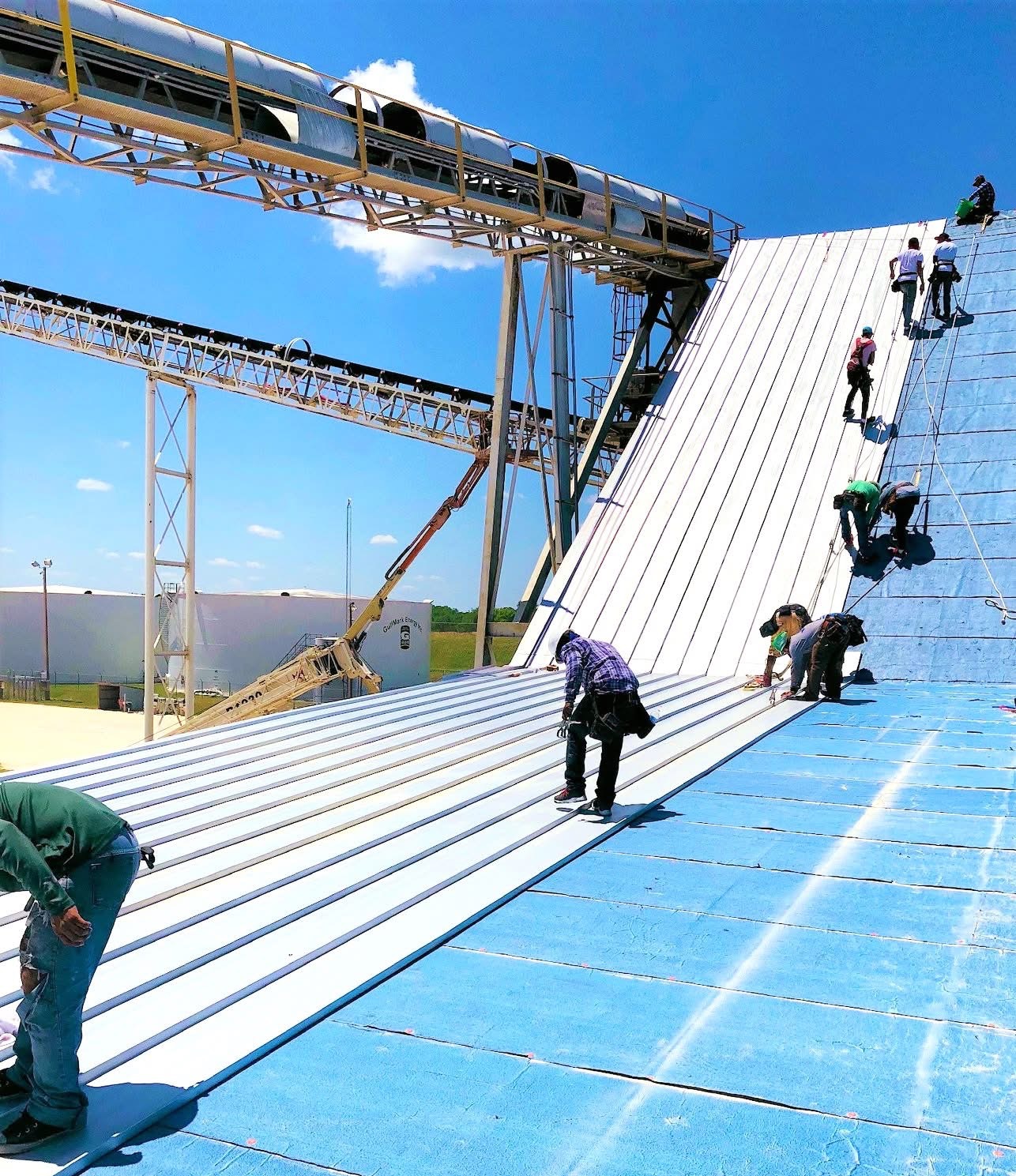 Commercial metal roof installation in Texas with standing seam panels and professional roofing crew working on industrial building
